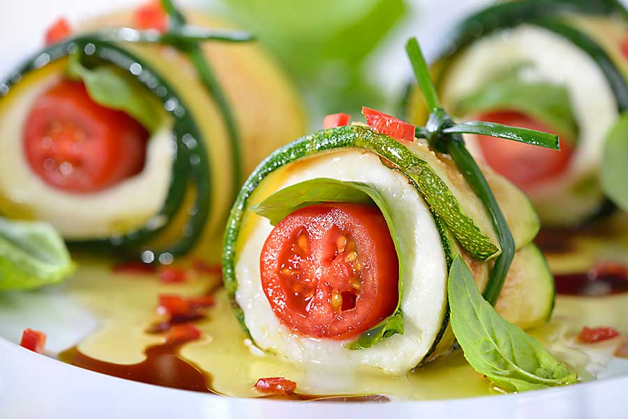 Caprese wrapped with fried zucchini slices, tied and knotted with chives.