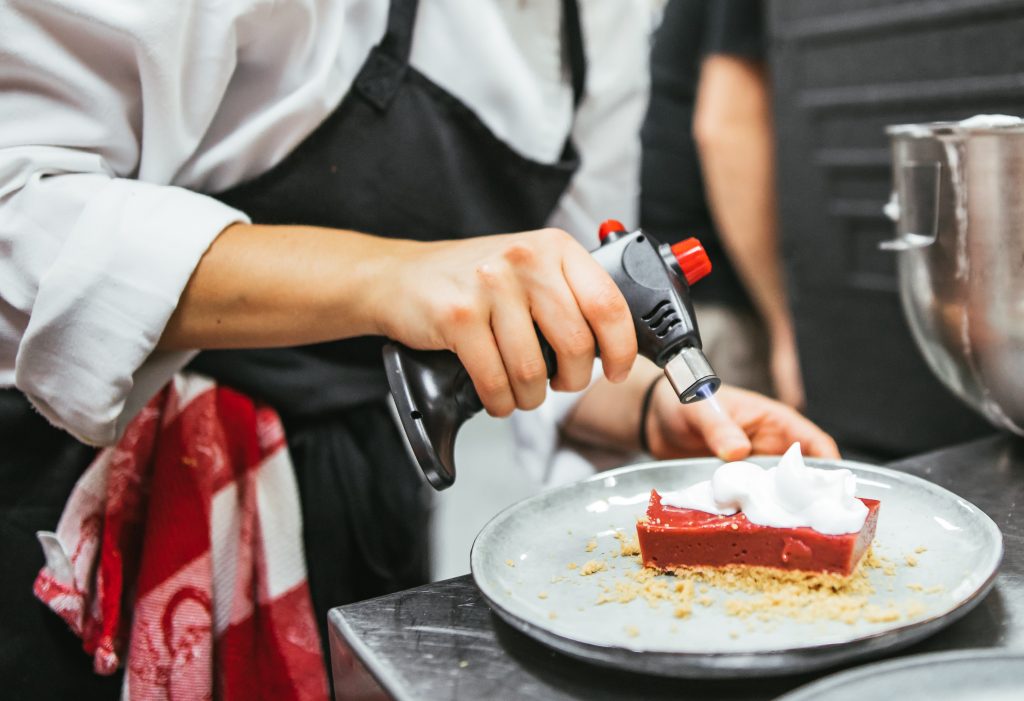 A female chef is torching a dessert