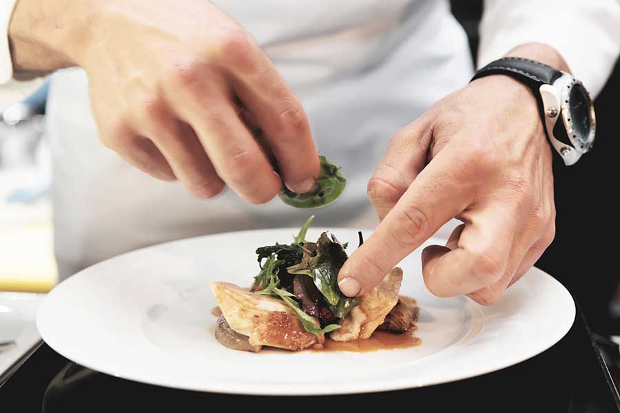 chef is plating a chicken dish