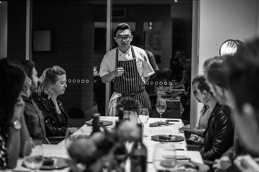 Chef explaining menu in front of dinner hosts and guests.